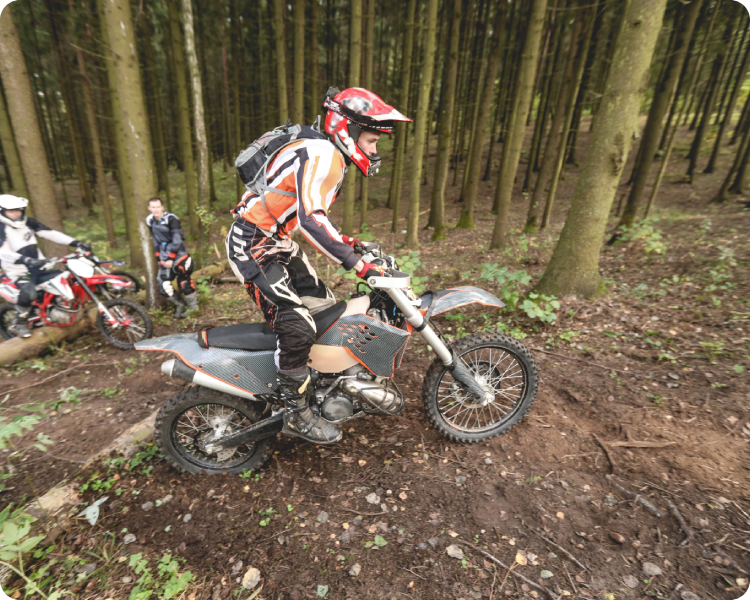 Motorcyclist riding dirt bike in forest.